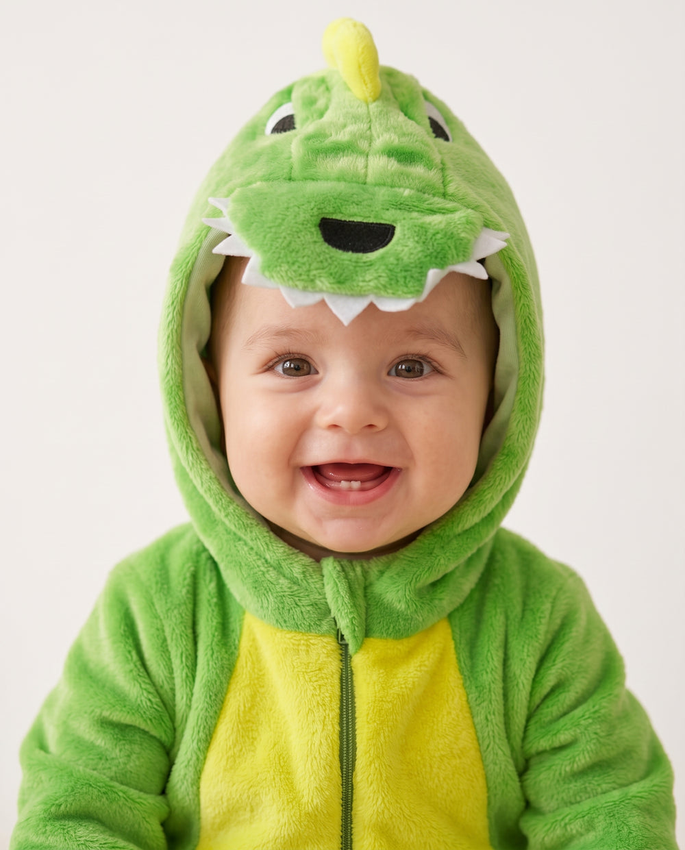 Gros plan sur la capuche dinosaure et le sourire de bébé